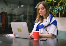 Young woman focused on laptop work in a modern cafe setting, surrounded by technology. job for girl