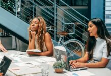 Diverse women engaging in a collaborative meeting at an office desk, focused on planning and innovation.
